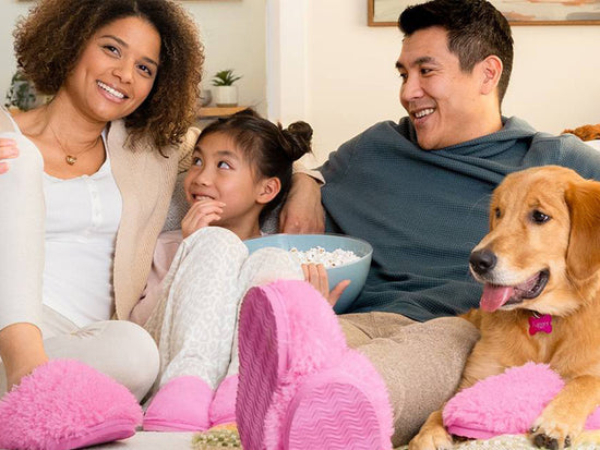 A family and their dog sits on a couch eating popcorn